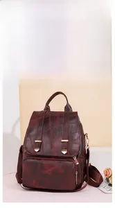 Detailaufnahme des weinroten Vintage-Rucksacks mit goldenen Reißverschlüssen und Schließen