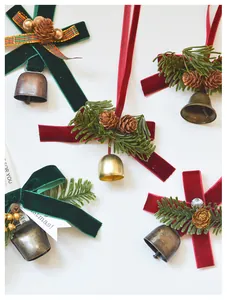 Detail of Christmas velvet bow ornaments with gold bells and artificial pine cone sprigs