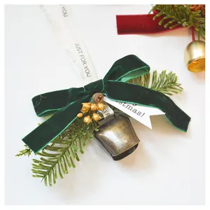 Detail of Christmas ornament with velvet bow, pine needles, and golden bells