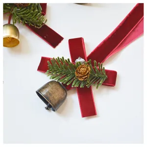 Close-up of Christmas velvet bow with pine needles, gold cones, and metal bells