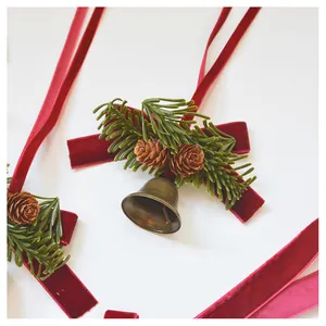 Close-up of Christmas bell with red velvet bow, pine needles and small pine cones