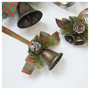 Detail of Christmas bell ornament with pine needles, cones and red plaid ribbon