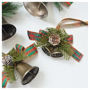 Detail of Christmas bell ornament with pine needles, cones and plaid ribbon on white background