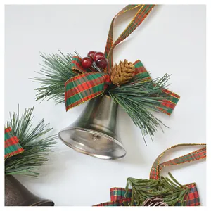 Close-up of Christmas bell with red and green plaid ribbon, pine cones and berries