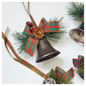 Close-up of Christmas bells with red plaid bows, pine needles, and golden pine cones