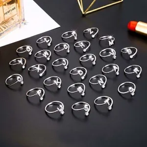 Makroaufnahme silberner Buchstabenringe mit Diamanten auf elegantem schwarzem Grund