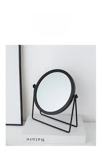 Detail of a minimalist black iron desktop mirror with a rotatable round frame design