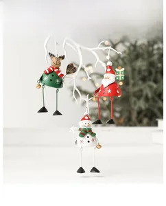 Detailed view of metal Santa, reindeer and snowman bell ornaments hanging on a white branch