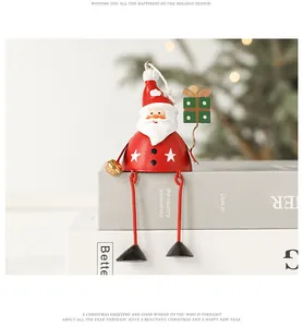 Detail of sitting Santa ornament with long metal legs and golden bell on books