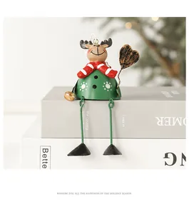 Detail of Christmas metal reindeer ornament with green bell body and red scarf on books