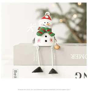 Detail of metal snowman bell ornament with long metal legs on festive book stack