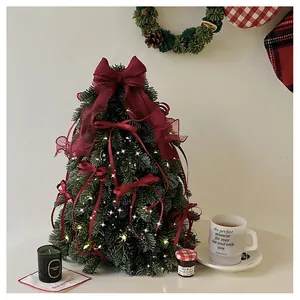 Detail of mini artificial PE Christmas tree with red velvet bows and warm LED lights