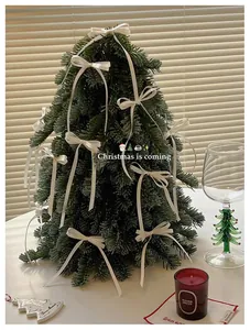 Close-up of artificial pine Christmas tree with white satin bows and festive decor