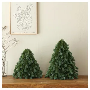 Close-up of two realistic PE pine mini Christmas trees on a wooden tabletop