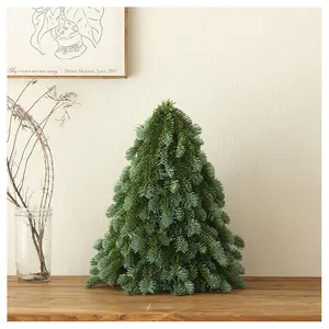 Detailed view of mini PE artificial Christmas tree with bow on a cozy wooden table