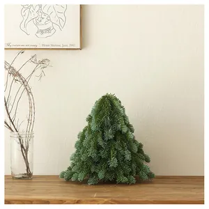 Close-up of a mini PE pine Christmas tree with bow on a wooden desk in a cozy room