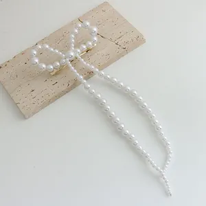 Détail d'une pince à cheveux nœud en perles avec de longs pompons élégants sur pierre
