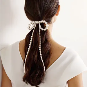 Détail d'une pince à cheveux nœud en perles avec de longues chaînes à pompons