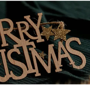 Dettaglio macro della targa in legno Merry Christmas con stelle glitterate oro appesa