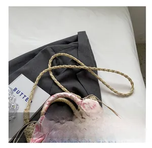 Detail of straw woven bag with pink floral scarf handle and thin shoulder strap