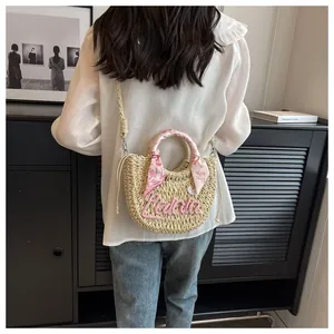 Detail of woven straw handbag featuring a pink floral scarf and adjustable shoulder strap