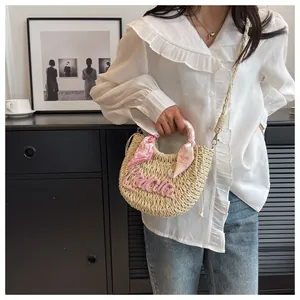 Detail of straw woven bag with pink Lala embroidery and floral scarf wrapped handle