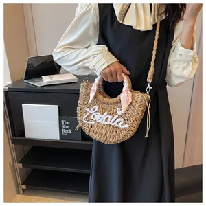 Detail of straw woven handbag with Lalala embroidery and floral scarf wrapped handle