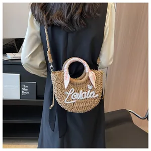 Model wearing a straw tote with floral silk handle and Lalala embroidery on back