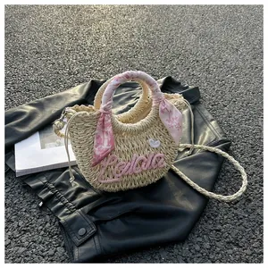 Detail of straw woven bag with pink Lalala embroidery and decorative floral handle scarf