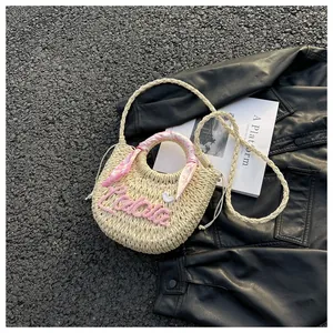 Detail of straw woven bag with pink scarf handle and Lalla embroidery on flat lay
