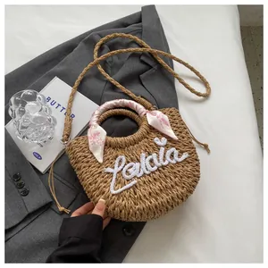 Straw handbag with Lalaia embroidery and pink floral silk scarf on a stylish background