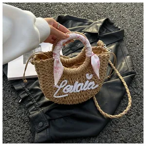 Detail of a beige woven straw tote with floral scarf handle and Lulala embroidery