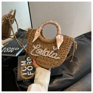 Detail of straw woven handbag with Lalaia embroidery and silk scarf handle on leather