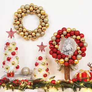Close-up of golden and red Christmas ball wreaths and mini white trees for festive decor