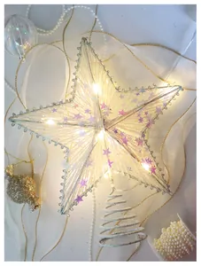 Close-up of a lit champagne sequin tree topper star with internal warm yellow LED lights