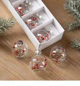 Detailed view of six clear glass Christmas balls with red berry fillers in a white box.
