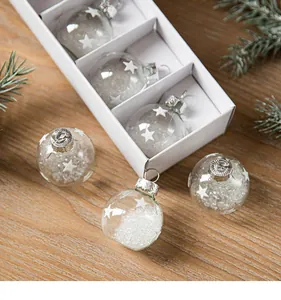 Close-up detail of clear glass Christmas balls with white stars and snow in box