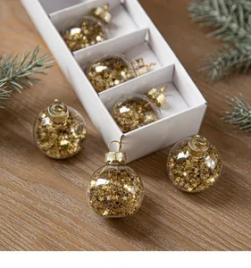Detailed view of transparent Christmas baubles filled with gold star-shaped sequins