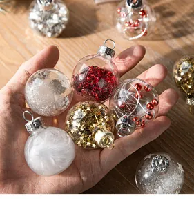 Close-up of clear decorative Christmas balls with glitter and feathers held in hand