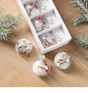 Detail view of clear glass Christmas ornaments with snow and red berries inside