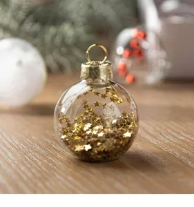 Macro detail of a clear glass Christmas ornament ball filled with shiny gold star sequins