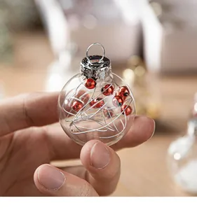 Close-up of a clear glass Christmas ornament ball with red beads and silver wire inside.