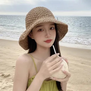 Detail of hand-woven straw sun hat with wide wavy brim and natural texture for beach vacation