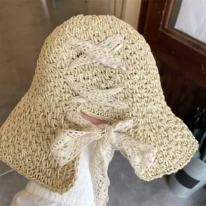 Detailed view of beige straw sun hat featuring elegant lace ribbons and bow decoration