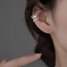 Close-up of a silver bow-shaped ear cuff in a minimalist hollow metal line design