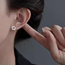 Close-up of star-shaped silver stud earrings with sparkling stones on model