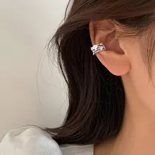 Detailed view of silver cat-shaped ear cuff with zircons on a model's ear