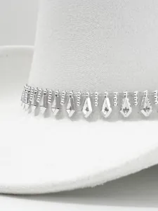 Dettaglio delle frange di strass argentati a forma di rombo su un cappello da cowboy bianco