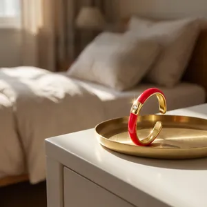 Detail of gold-plated open bangle with red enamel inlay and central sparkling zircon