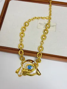 Detailed macro view of gold evil eye pendant with blue enamel and pearl tassels
